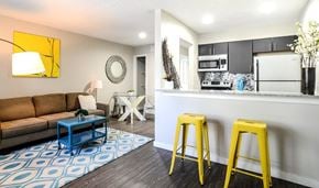 Austin apartment for rent - A living room with a brown couch, a blue coffee table, and yellow stools.
