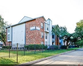 Kenner apartment for rent - a brick and white building with a yard and a fence