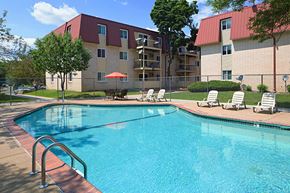 St. Paul apartment for rent - a swimming pool with chairs and a building in the background