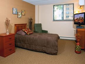 St. Paul apartment for rent - Bedroom with a dresser, a green chair in the corner, and a dresser with a TV on it