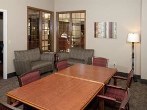 St. Paul apartment for rent - Conference room with wooden table, surrounded by maroon red chairs, and gray sofa chairs in the corner