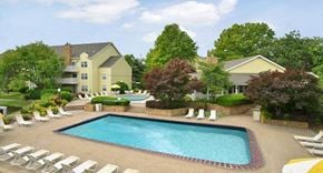 Fairview Heights apartment for rent - a swimming pool with chairs and a building in the background
