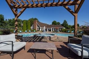 Ypsilanti apartment for rent - a backyard with a pool and patio with chairs and a table