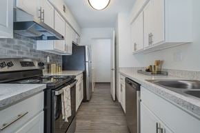 Ypsilanti apartment for rent - a kitchen with white cabinets and a black stove and a refrigerator
