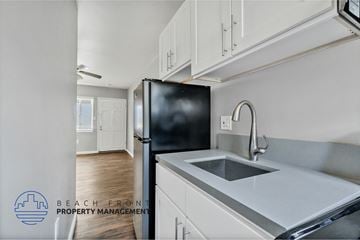 Long Beach apartment for rent - a kitchen with white cabinets and a sink and a black refrigerator