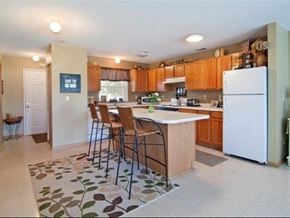 Farmington townhouse for rent - a kitchen with a white refrigerator and a bar with chairs