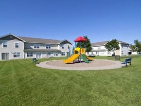 Farmington townhouse for rent - a playground in the middle of a yard in front of an apartment building
