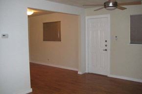 Austin apartment for rent - an empty living room with a white door and a ceiling fan