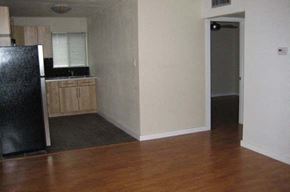 Austin apartment for rent - an empty kitchen with wood floors and a black refrigerator