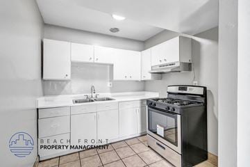 Anaheim apartment for rent - A kitchen with a black stove top oven and white cabinets.