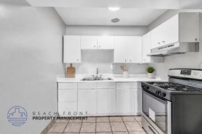 Anaheim apartment for rent - A modern kitchen with white cabinets and a black stove top oven.