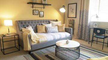 Cockeysville apartment for rent - A grey tufted sofa with a white throw blanket sits in a living room with a black coffee table in front of it.