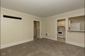 Seattle apartment for rent - an empty living room with a kitchen in the background