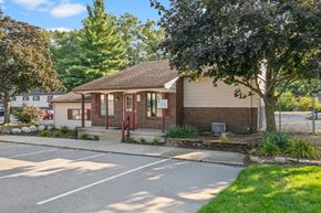 Wyoming apartment for rent - A small building with a red door is surrounded by a parking lot.