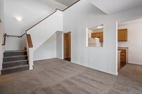 Allegan apartment for rent - A spacious living room with a staircase and a mirror on the wall.
