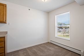 Allegan apartment for rent - A room with a window showing a view of a tree and a building outside.