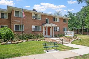 Grand Rapids apartment for rent - A brick building with a green bench in front of it.
