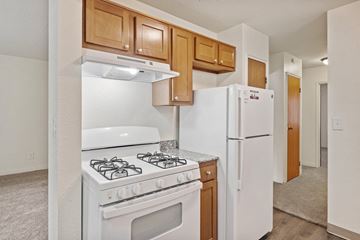 Grand Rapids apartment for rent - A white stove and refrigerator in a kitchen with wooden cabinets.