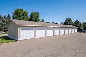Wyoming apartment for rent - A long white garage with a brown roof is surrounded by a gravel lot.