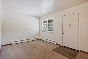 Wyoming apartment for rent - A room with a carpeted floor, a door, and a window with a view of trees.