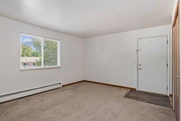 Wyoming apartment for rent - A room with a carpeted floor, a window, and a door.