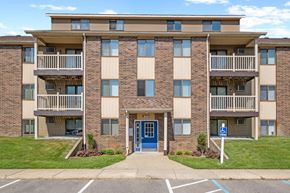 Grandville apartment for rent - A large apartment building with a blue door and a handicap sign in front.