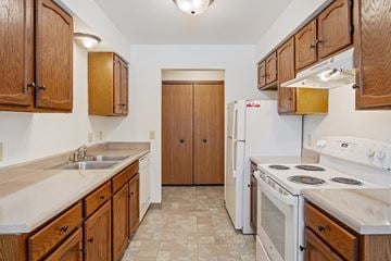 Grandville apartment for rent - A kitchen with wooden cabinets and a white stove top oven.