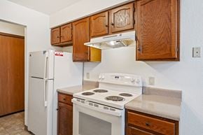 Grandville apartment for rent - A kitchen with a white stove and a white refrigerator.