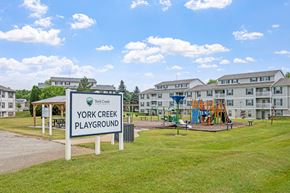 Comstock Park apartment for rent - A playground sign for York Creek Playground stands in front of a building.