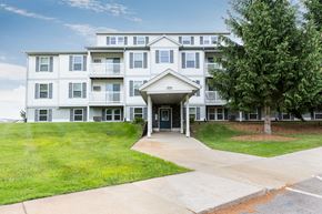 Comstock Park apartment for rent - a large white apartment building with a tree in front of it