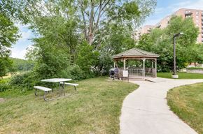 Minneapolis apartment for rent - A gazebo sits in the middle of a grassy area with a picnic table and a concrete walkway.