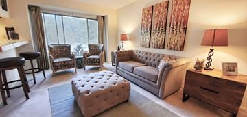 Columbia apartment for rent - A living room with a grey couch, two chairs, a table, and a painting on the wall.