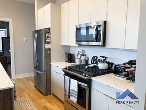 Chicago apartment for rent - a kitchen with white cabinets and a stove and a refrigerator