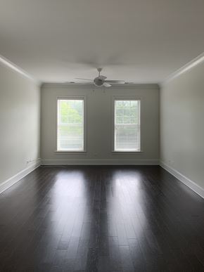 Evanston apartment for rent - an empty living room with a ceiling fan and two windows