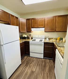 Virginia Beach apartment for rent - A kitchen with white appliances and brown cabinets.