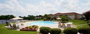 Virginia Beach apartment for rent - a swimming pool with chairs and umbrellas in front of a building