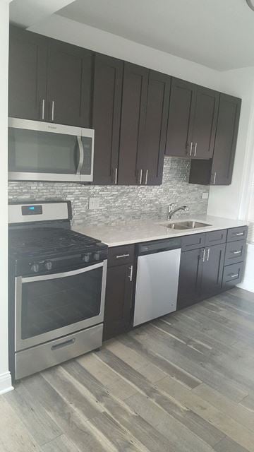 Chicago apartment for rent - a kitchen with dark cabinets and a stove and a sink