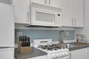 Denver apartment for rent - A white gas stove is in a kitchen with a white refrigerator and a white microwave above it.