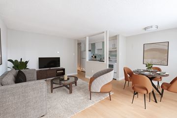 Denver apartment for rent - A living room with a grey couch, a brown chair, a brown table and a television.