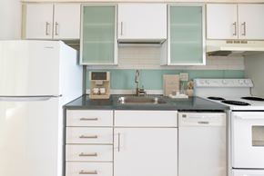 Denver apartment for rent - A white refrigerator is in a kitchen with white cabinets and a black counter.