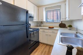 Denver apartment for rent - A black refrigerator is in a kitchen with white cabinets.
