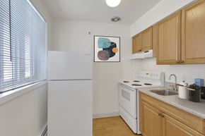 Denver apartment for rent - a kitchen with white appliances and wooden cabinets and a window