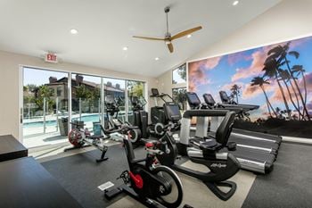 A gym with cardio equipment and a view of a swimming pool