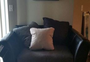Watford City apartment for rent - a black leather couch with white pillows on it
