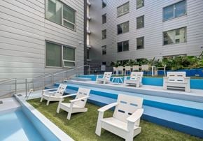 New Orleans apartment for rent - A pool with white chairs and a building in the background.