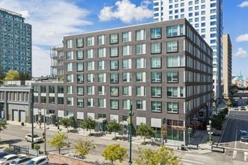 New Orleans apartment for rent - A large building with many windows is in the middle of a city street.