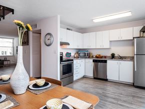 Gainesville townhouse for rent - a kitchen with white cabinets and stainless steel appliances and a dining table