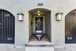 San Francisco apartment for rent - A building with the number 1025 on it has a black door and two windows with lights on them.