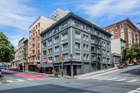 San Francisco apartment for rent - A street view of a city with a grey building in the center.