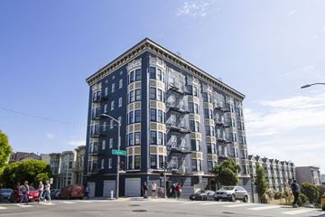 San Francisco apartment for rent - A large building with a blue facade is surrounded by cars and people.